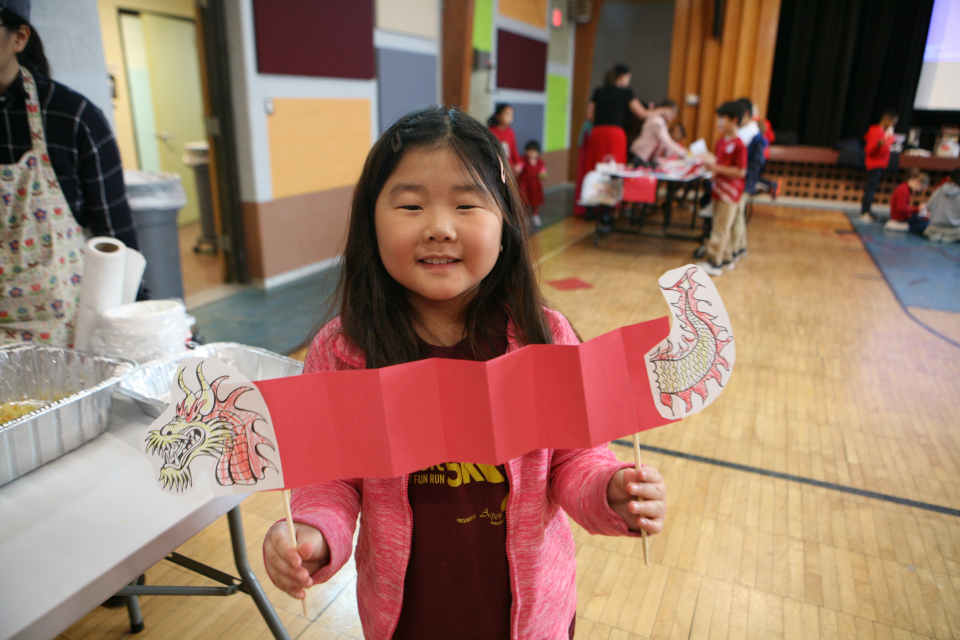 young girl showing the paper dragon she made