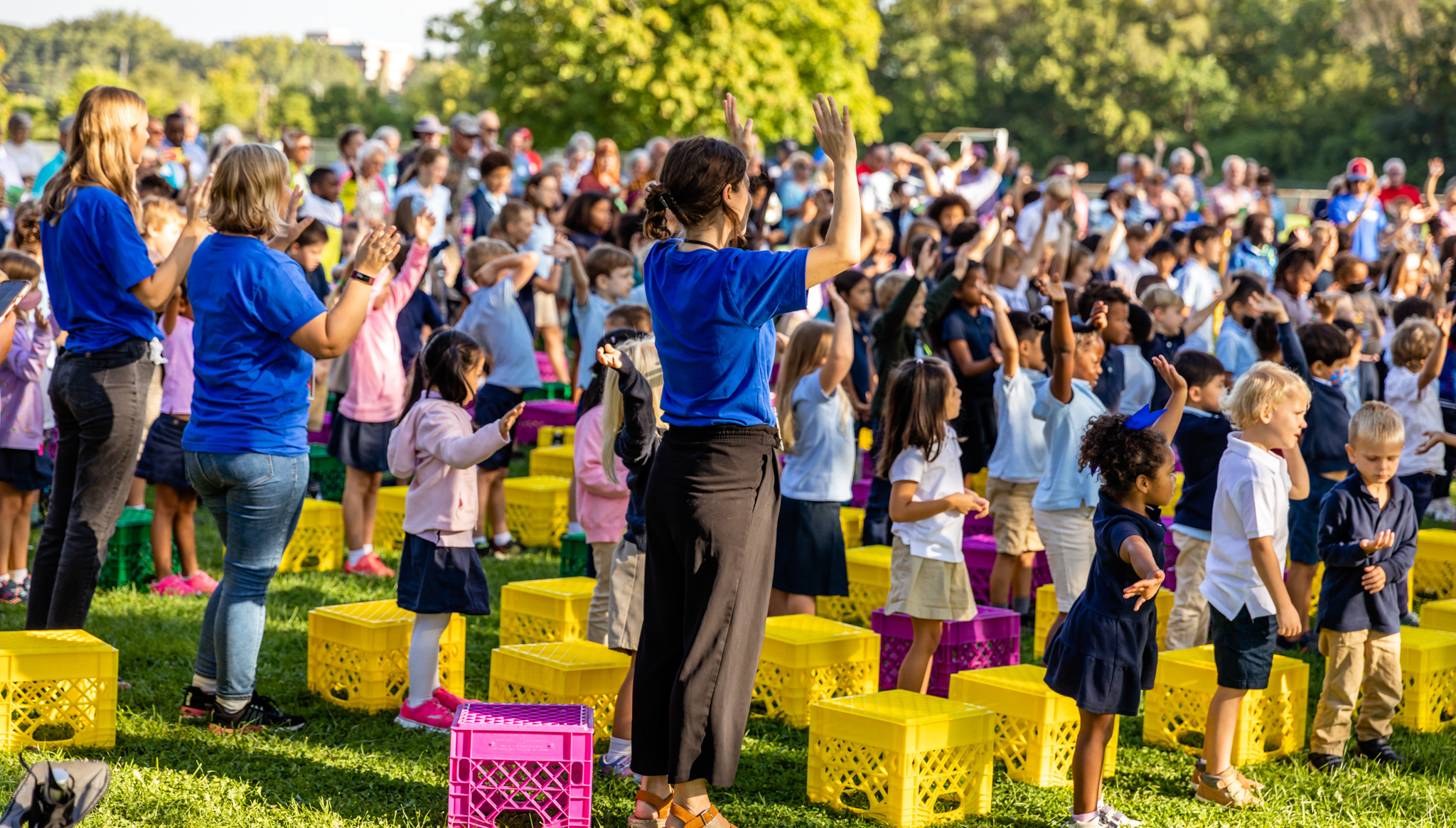 children outside sitting on milk crates